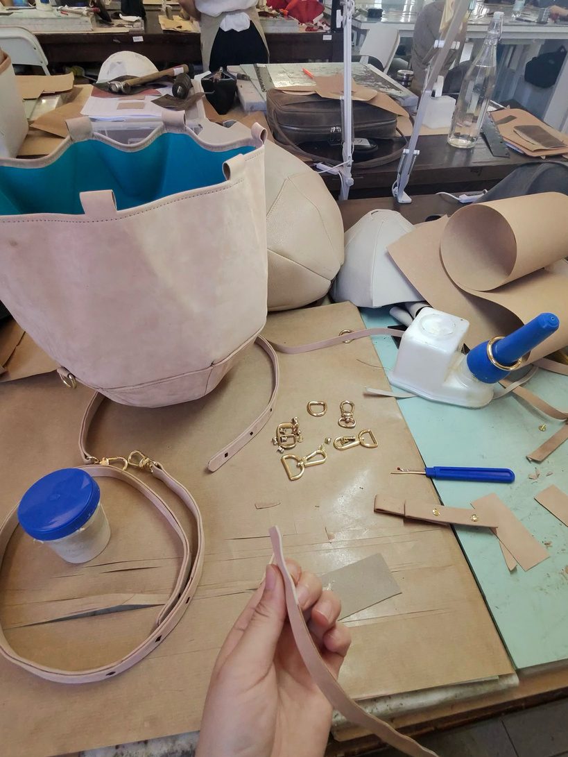 Reverive leather goods under construction in the Florence workshop, with gold hardware and bioluminescent turquoise lining